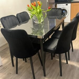 A dining table with black chairs and a vase of red and orange tulips.