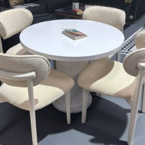 Aria Round Table Set with a white round table and four ivory upholstered chairs in a showroom.