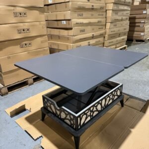 A lift-top coffee table in front of stacked cardboard boxes in a warehouse.