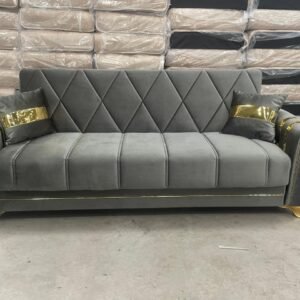 Gray sofa with gold accents and diamond-patterned backrest in a warehouse.