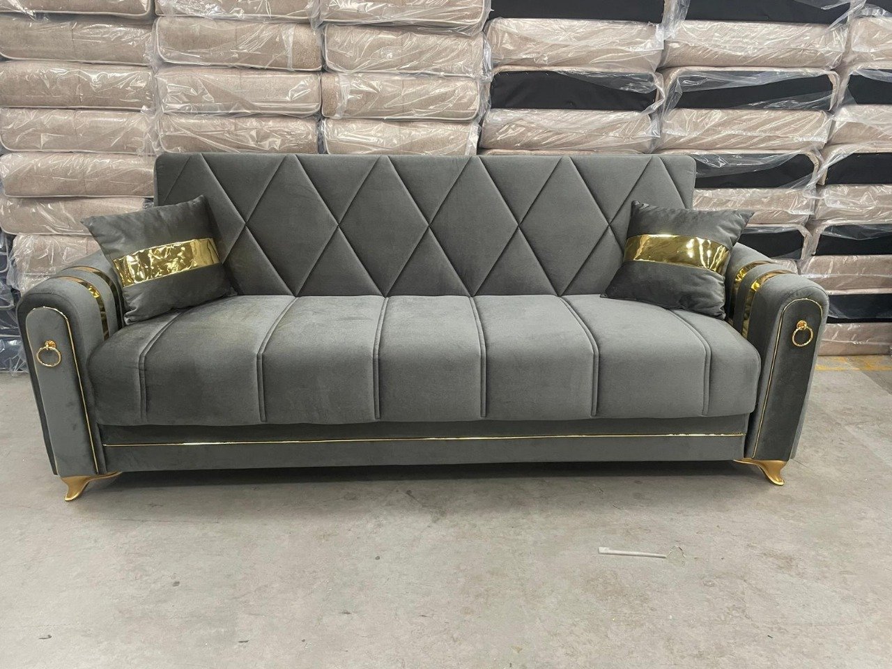 Gray sofa with gold accents and diamond-patterned backrest in a warehouse.