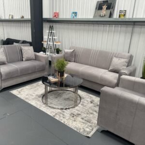 Showroom with modern gray Ebono Sofa Bed, loveseat, and armchair, centered around a black coffee table.