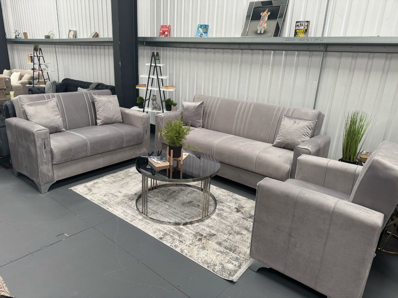 Showroom with modern gray Ebono Sofa Bed, loveseat, and armchair, centered around a black coffee table.