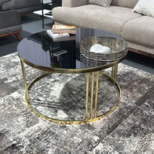 Elara Round Coffee Table with black glass and gold metal base in a living room.