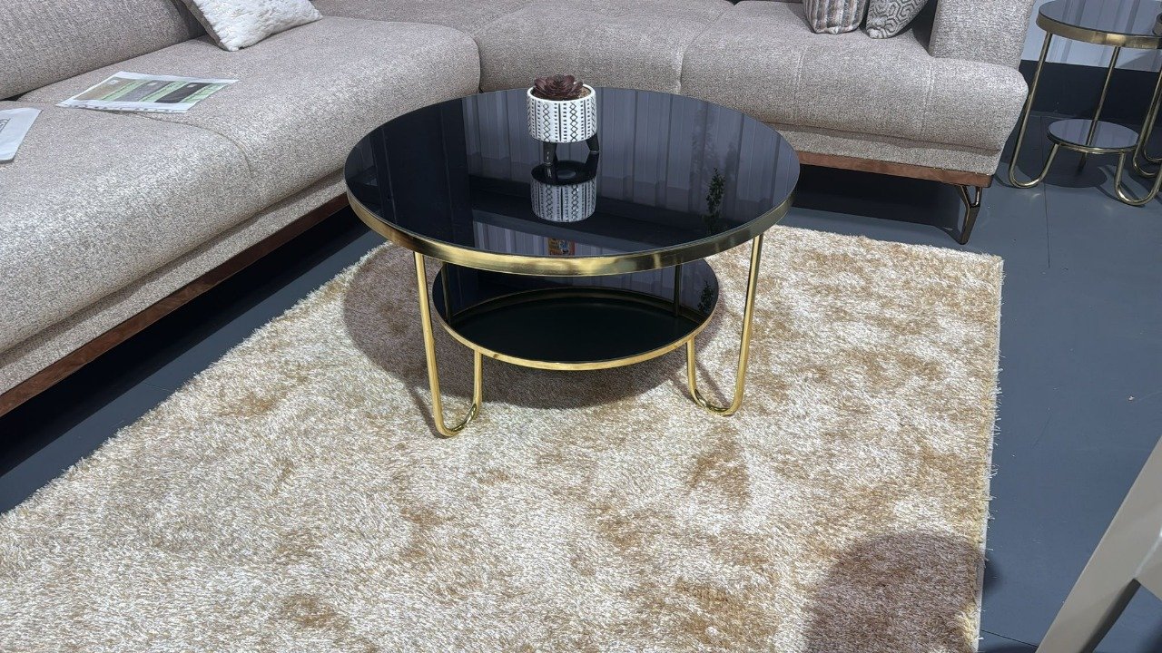 Round Everett Coffee Table with black glass top and gold frame in a modern living room.