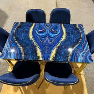 Rectangular table with blue and gold abstract design and five blue upholstered chairs.