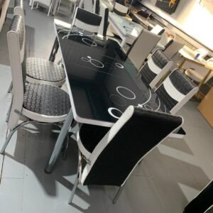 HaloStretch Dining Table with a black glass top and six matching chairs in a showroom.