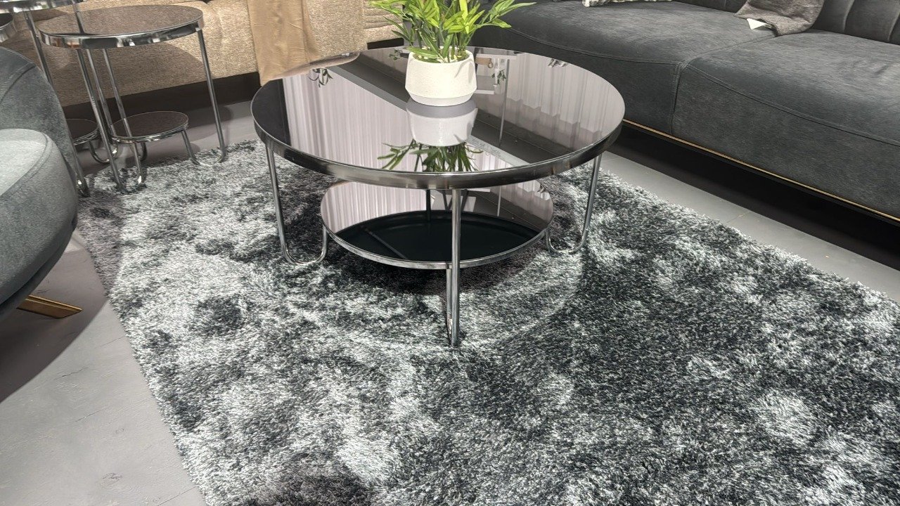 Haven Coffee Table with black glass top and metal frame on a gray rug in a modern living room.