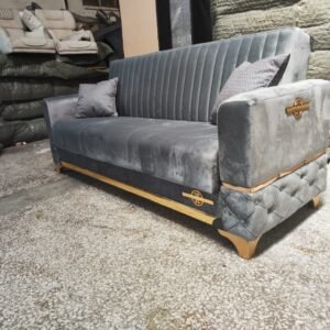 Marcelli Sofa Bed in a warehouse setting, upholstered in gray velvet with gold accents.