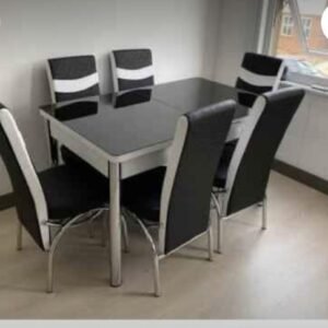 A modern dining set with a black table and six matching chairs with black and white upholstery.
