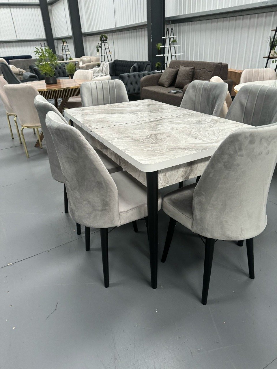 OakHaven Dining Set with a marble-like table and gray upholstered chairs in a showroom.