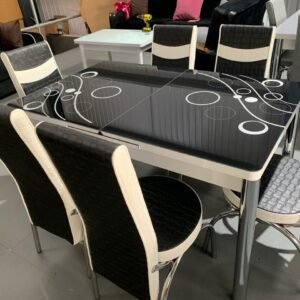 OptraGlass Extendable Table with a black glossy surface and white circular patterns, surrounded by six black and white chairs.