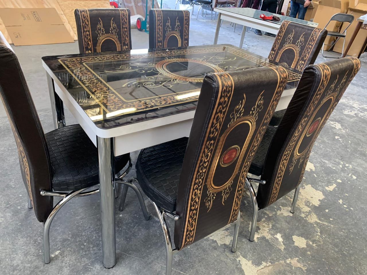PrismaPull Dining Table with six black and gold patterned chairs in an indoor setting.
