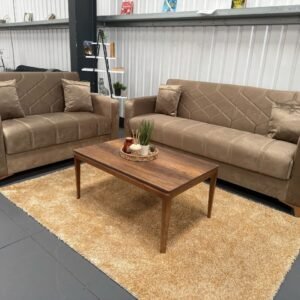 Two Romano Sofa Beds in light brown fabric with a wooden coffee table on a beige rug in a showroom.