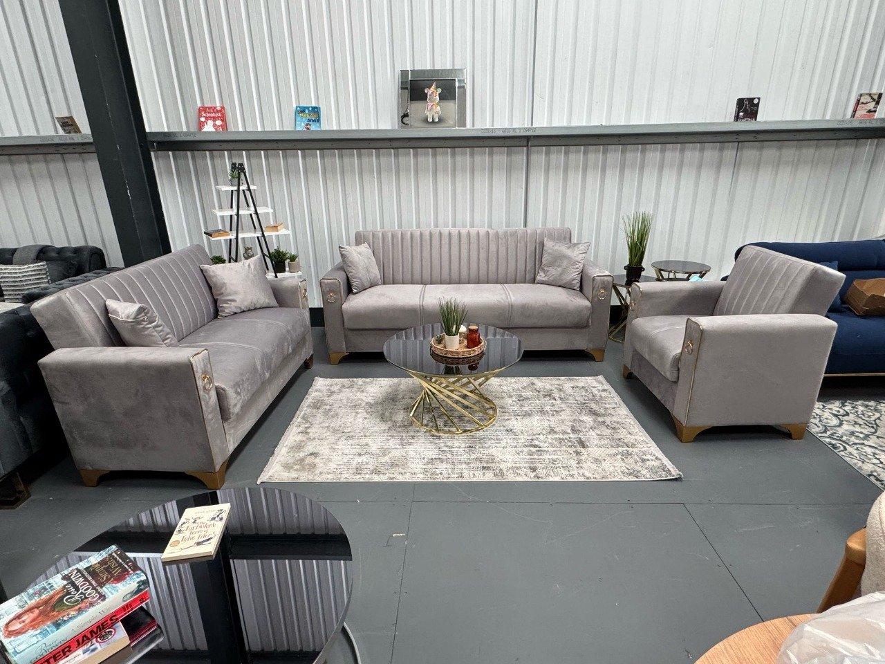 A set of Siena Sofa Bed furniture in light gray with gold accents, featuring a sofa, loveseat, and armchair.