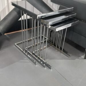 Modern metallic nesting tables next to a gray sofa.