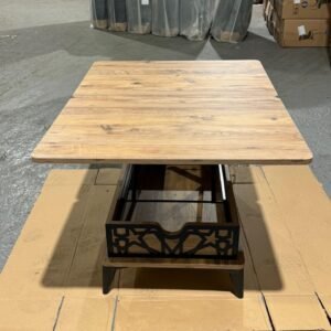 Wooden table with black metal accents on a cardboard base in a warehouse.