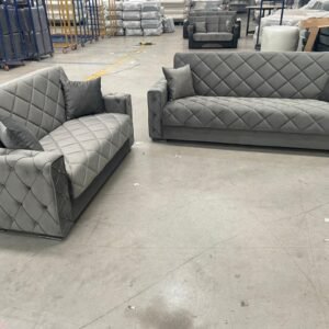 Two gray tufted sofas in a warehouse.