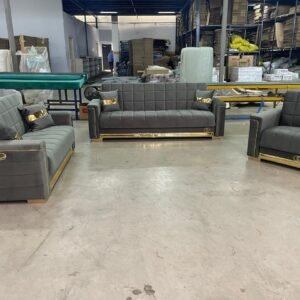 Gray and gold furniture set with two sofas and an armchair in a warehouse setting.